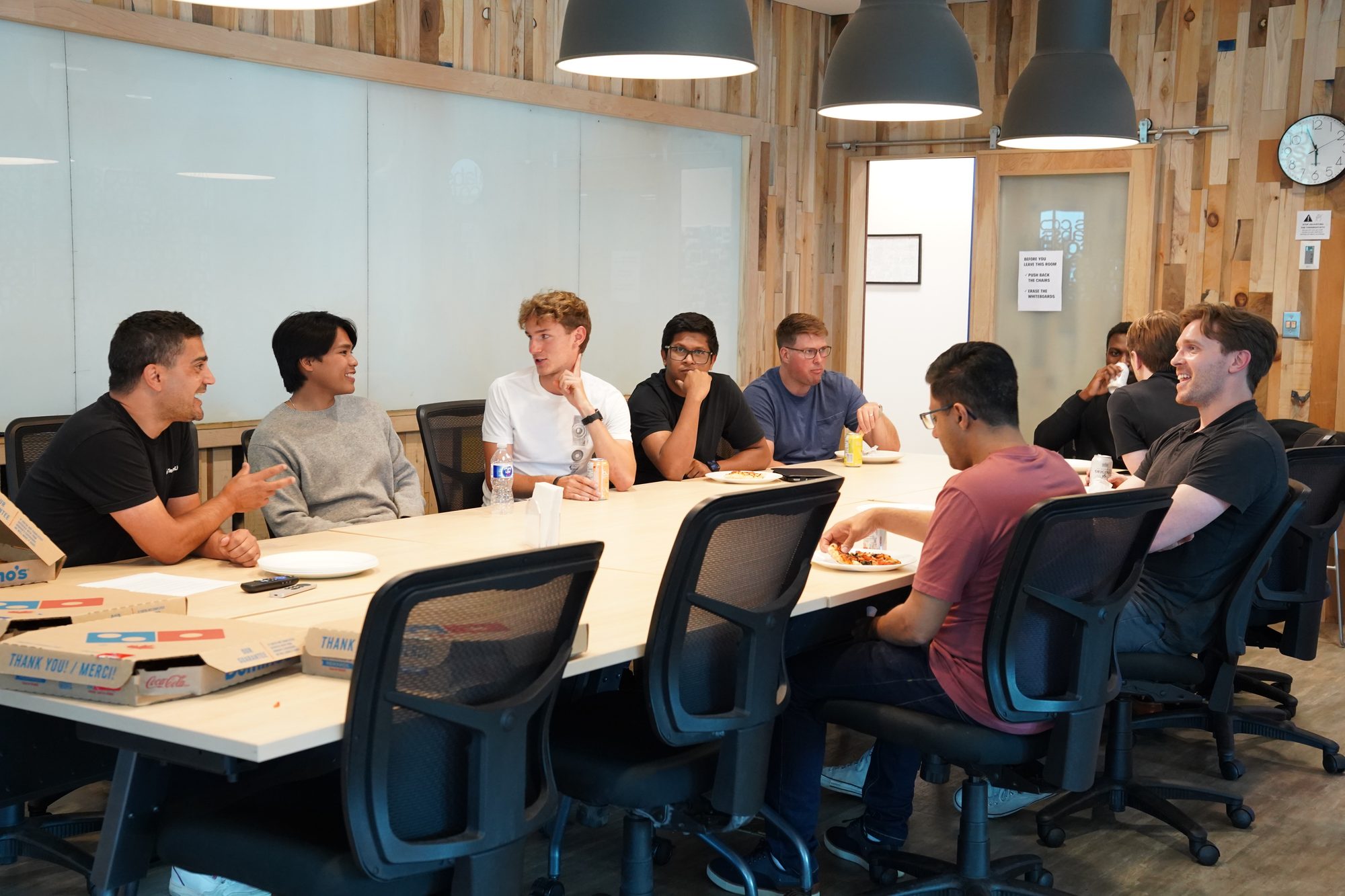Young founders in discussion around a boardroom table with pizza boxes at a Co.Labs event, Saskatoon.